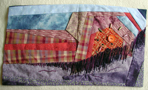 An abstract fabric interpreation of a mountain sunset, using crazy quilting techniques and plain and beaded embroidery.