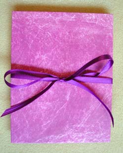 The closed accordion book coveredin painted tyvek and tied with a ribbon.