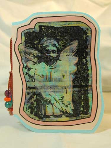 A shaped pamphlet stitch booklet with an acrylic background and image from Anima Designs.