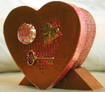 An angled view of a boxed accordion book featuring flatmarble, brass charms and beedz.