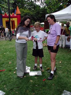 Amanda teaches a young boy and his mother about drop spindle spinning.