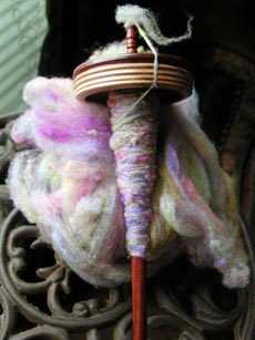 A look at the rainbow targhee roving and my spindle with the spun yarn on it.