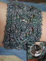 A warmlet or cross between a wrist warmer and bracelet knit from handspun yarn and closed with an antique glass button.